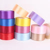 A stack of satin craft ribbons in various pastel colors including purple, blue, pink, and gold.