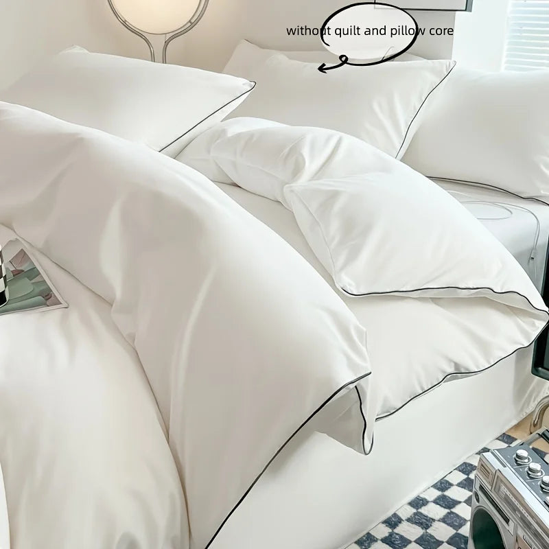A close-up of a white duvet cover set with a black piping detail on a bed, showing the fabric texture.