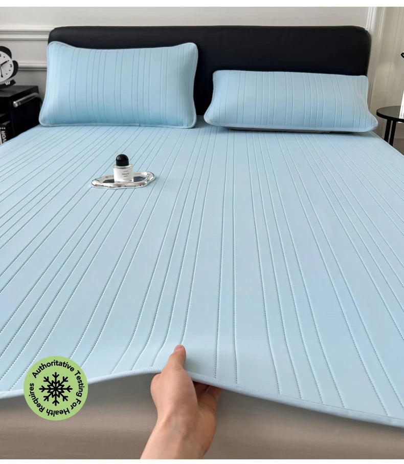 Light blue cooling ice silk bed pad placed on a bed with dark gray bedding and pillows.