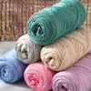 A stack of multicolored reusable elastic yarn in various shades of teal, pink, and beige for crafting