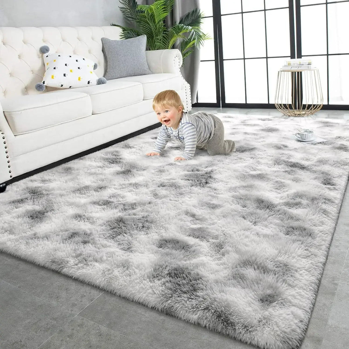 A fluffy gray plush carpet is spread on a floor in front of a white leather sofa and large windows.