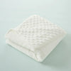 A white, quilted baby name swaddle blanket folded neatly on a light blue surface.