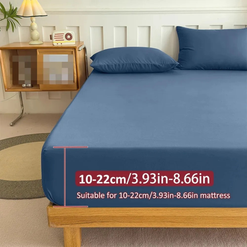 A blue fitted bed sheet is displayed on a wooden bed frame with a label indicating its size compatibility.