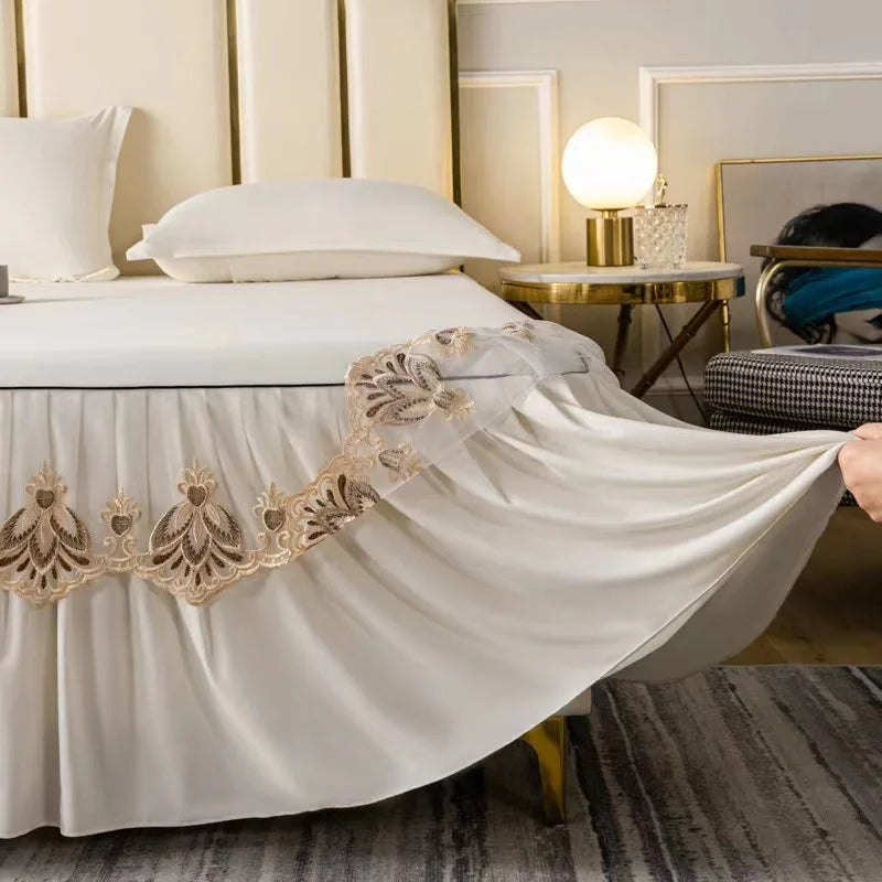 White embroidered cotton bedspreads and pillowcases draped over a white bed with gold accents.
