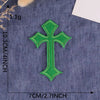 A single green cross embroidery patch on a dark blue fabric background.