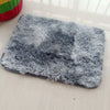 A gray faux fur rug placed on a light wooden surface.