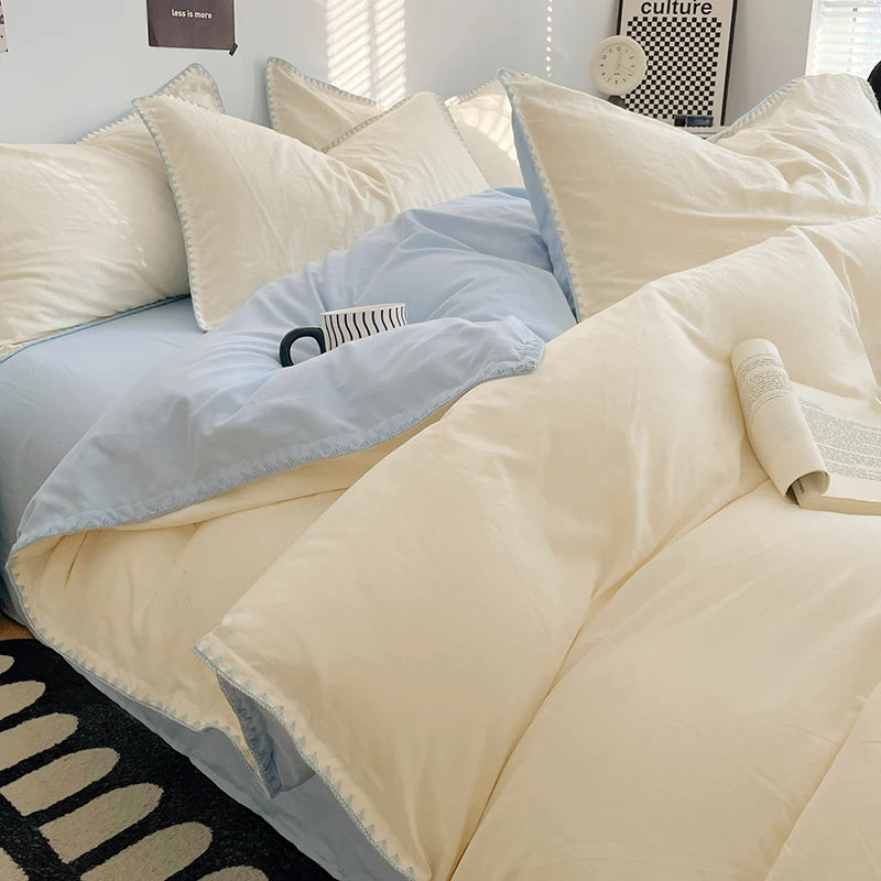 A close-up of a luxurious beige and light blue washed cotton bed linen set featuring pillows and bedding.