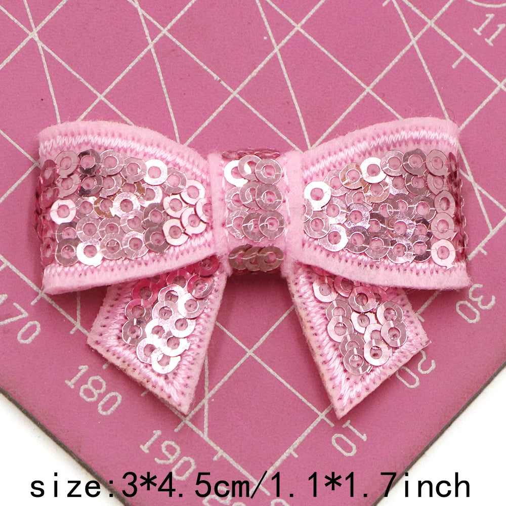 Pink sequin bow patches for DIY decoration shown on a pink cutting mat.