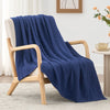 A deep blue quilted blanket draped over a wooden chair on a light rug.