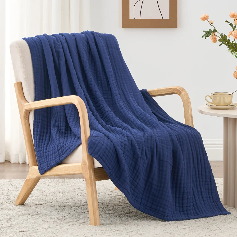 A deep blue quilted blanket draped over a wooden chair on a light rug.