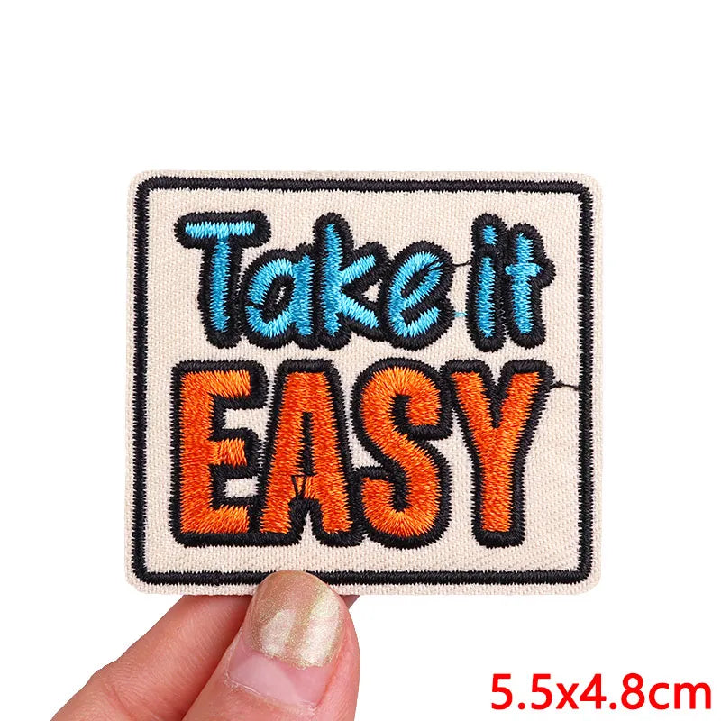 A square embroidered patch with the text Take it EASY in blue and orange thread.
