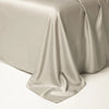 A draped, silky beige luxury Egyptian cotton bedding set covering a surface.