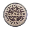 A circular embroidered patch featuring various letters and symbols in dark brown on a light background.