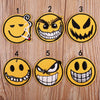 Six embroidered patches showing various angry and menacing emoji faces on a wooden background.