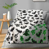 A black and white glow-in-the-dark bat and spider print coral fleece blanket displayed on a gray rug.