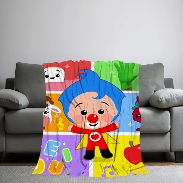 A colorful plush throw blanket featuring cute cartoon characters and musical notes draped over a gray sofa.