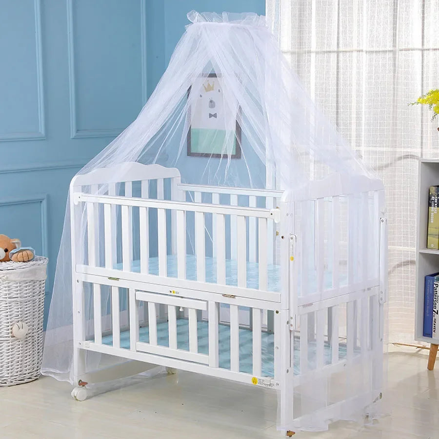 A white crib with a sheer white mosquito net draped over it, displayed in a light blue room.