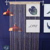 Decorative crystal beaded string curtains hanging against a dark blue background with framed art.