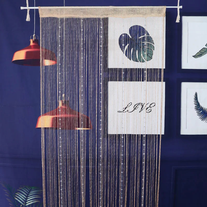 Decorative crystal beaded string curtains hanging against a dark blue background with framed art.