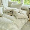 A light green and white checkered duvet cover set with matching pillows on a bed.