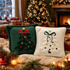 Two embroidered Christmas tree velvet pillows resting on a knitted surface near a decorated fireplace.