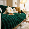 A deep emerald green plush rabbit sofa cushion with white and gold accents on a light wood background.