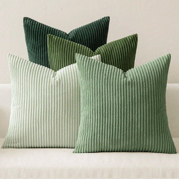 A set of four textured throw pillows in shades of sage green and pale mint green.