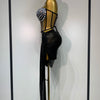 A black performance set displayed on a gold mannequin with dangling silver beads.