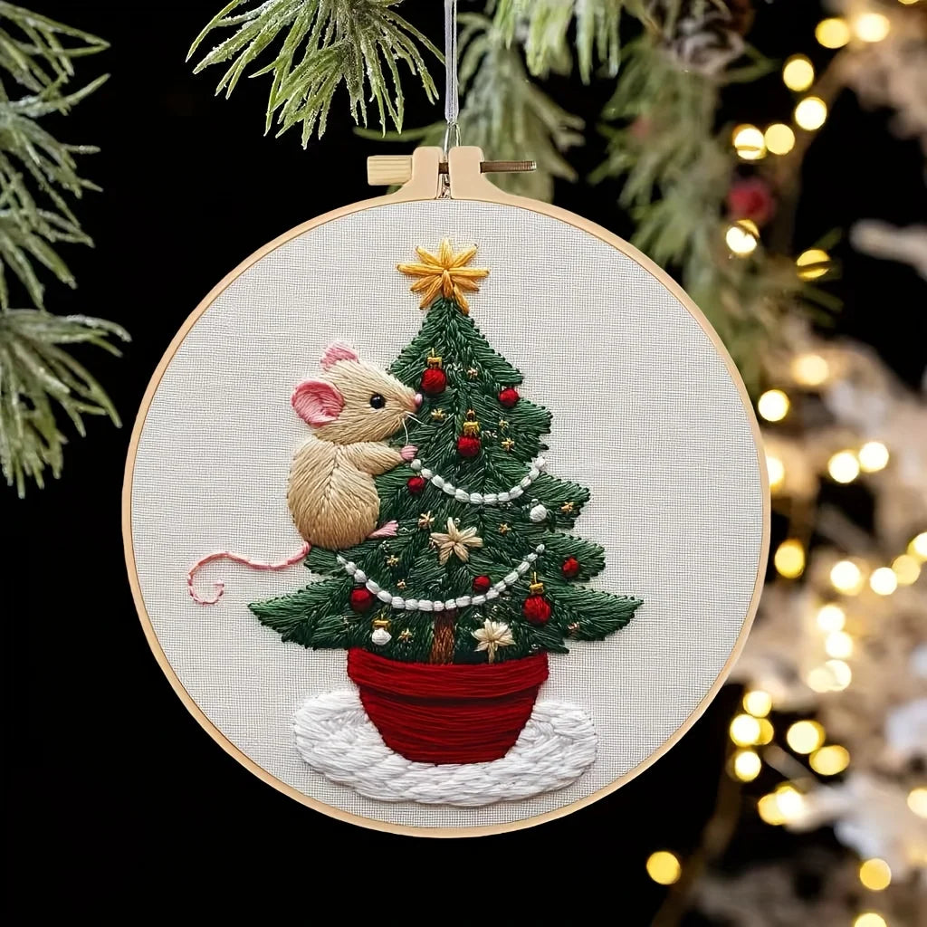A hand embroidery kit featuring a small, fluffy mouse nestled in a festive Christmas tree design.