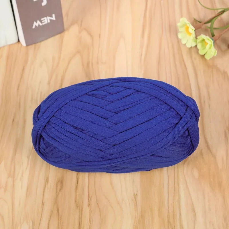 A ball of deep blue flat thread yarn for crafting and sewing lying on a wooden surface.