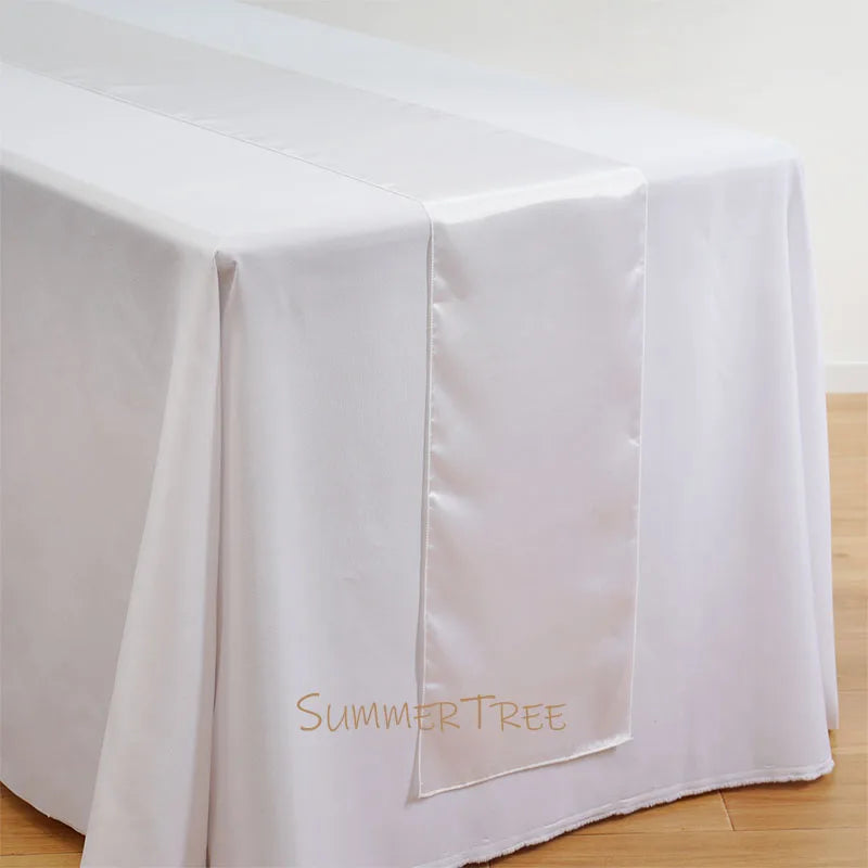 Elegant satin white table runner draped on a white tablecloth.