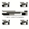 A set of geometric placemats and a table runner featuring shades of gray, black, and white.