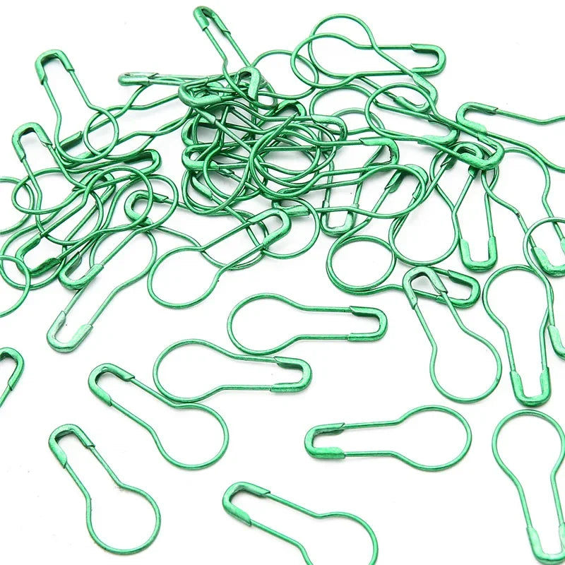 A pile of green safety bulb pins used for knitting and sewing.