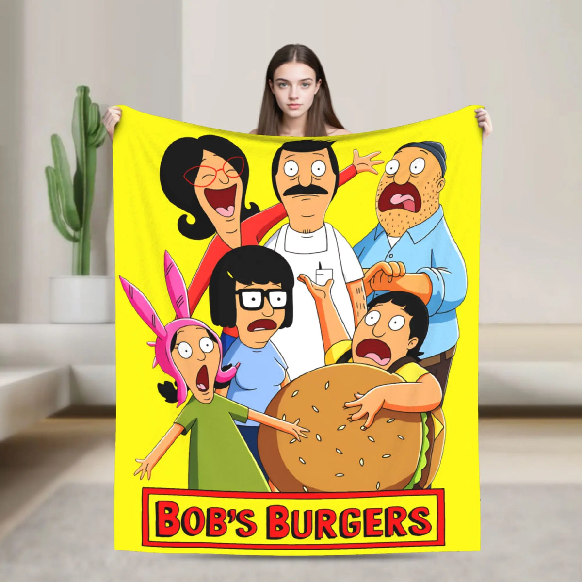 A yellow throw blanket featuring characters from Bob's Burgers, including Tina Belcher and Linda Belcher.