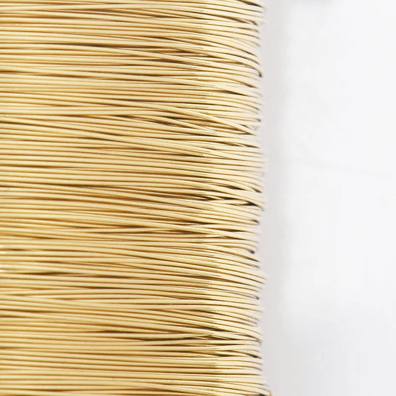 A tightly wound spool of thin, golden copper-colored steel wire for crafting.