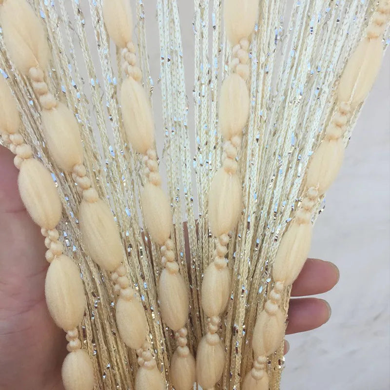 Close-up of a hand holding long strands of glitter fringe door curtain for home decor
