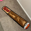 A brown decorative cigarette shaped floor mat with a red and white logo on the end.