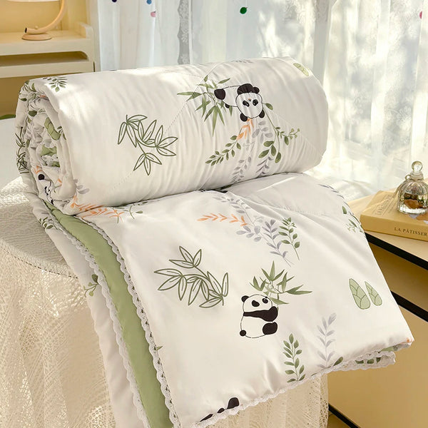 White quilt with a panda print featuring green leaves and stems, displayed on a light-colored surface.