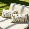 Three floral embroidered throw pillow covers in cream and sage green on a light beige outdoor sofa.