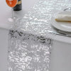 Silver sequin glitter table runner displayed on a white table with a glass and plate.