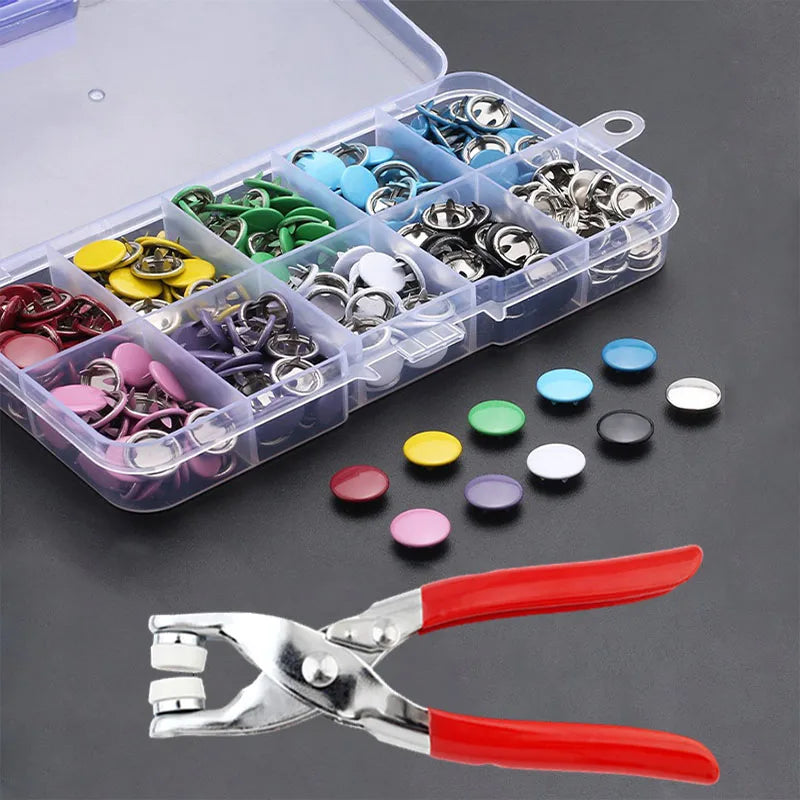 A clear plastic box filled with various metal prong snap button fasteners and a pair of silver and red pliers.