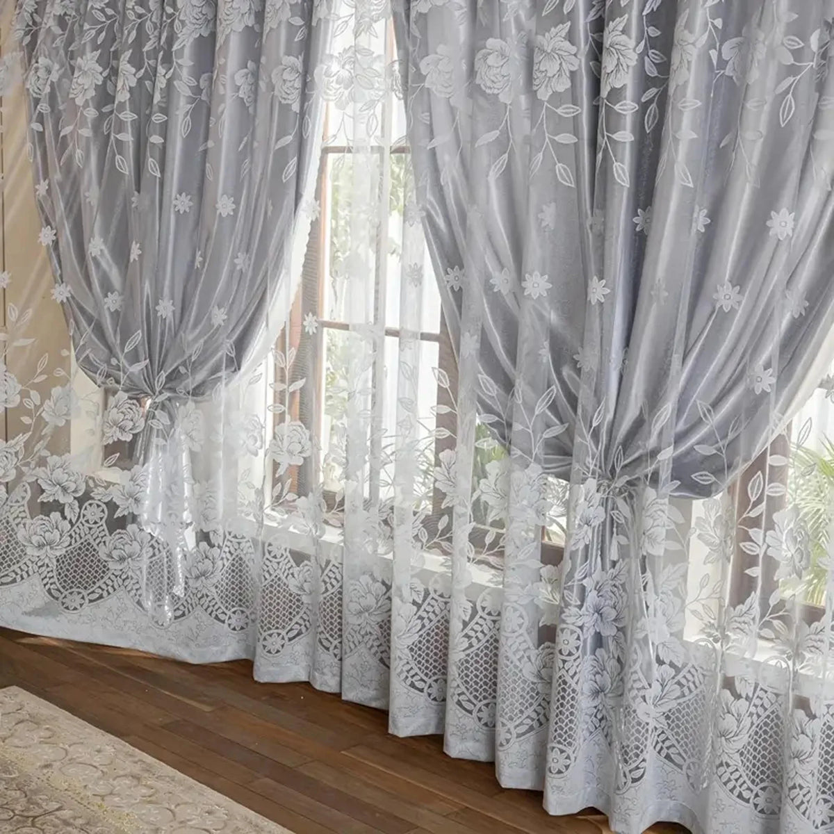 Gray vintage floral blackout curtains hanging in a window with sheer white lace undercurtains