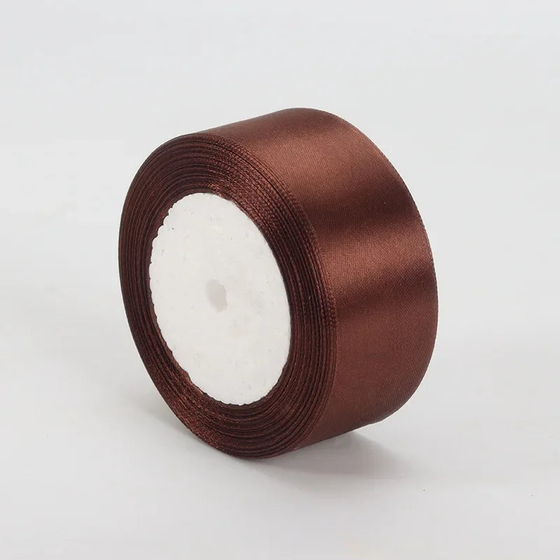 A roll of satin ribbon in a rich brown color used for crafts and gift wrapping.