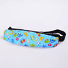A colorful fabric head support for a baby car seat featuring various toy-themed shapes and colors.