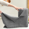 A hand is holding a gray reusable microfiber cleaning wipe product, showing its texture and shape.