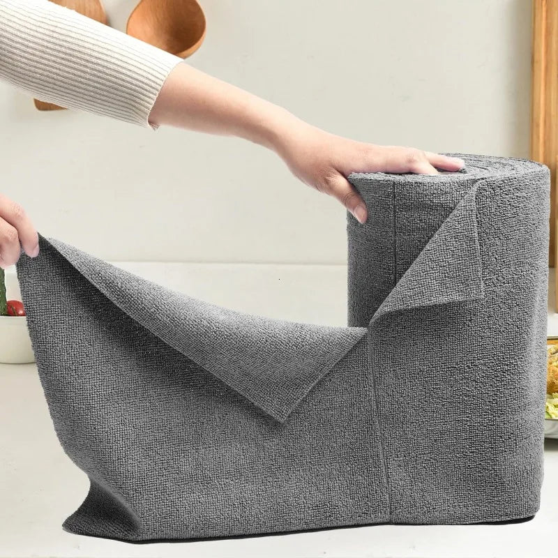 A hand is holding a gray reusable microfiber cleaning wipe product, showing its texture and shape.