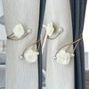 Close-up of light gray and dark blue curtains tied with elegant white rose pattern fabric and adjustable metal buckles
