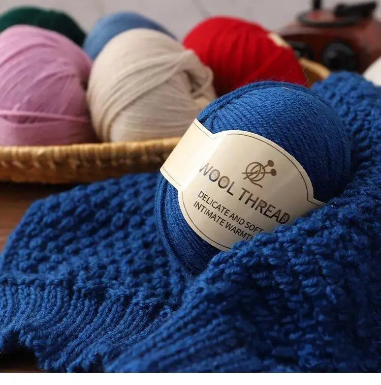 A close-up of a hand-knitted blue wool scarf featuring a white label that reads Wool Thread Delicate and Soft Intimate Warmth