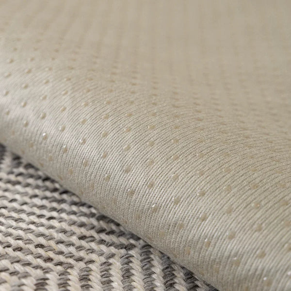 A beige anti-slip sofa cover fabric rolled out on a textured gray surface.