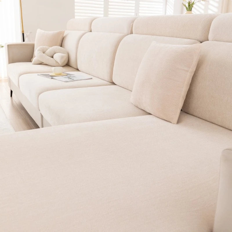 A light beige universal elastic sofa cover with a full backrest shown in a modern living room setting.